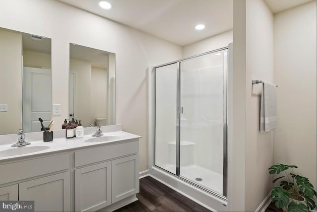 bathroom with hardwood / wood-style flooring, vanity, toilet, and walk in shower