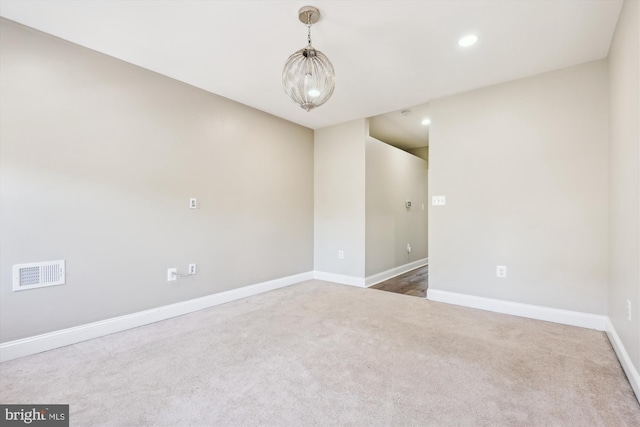 carpeted spare room with an inviting chandelier