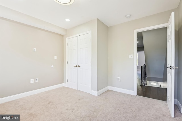 unfurnished bedroom featuring light carpet and a closet