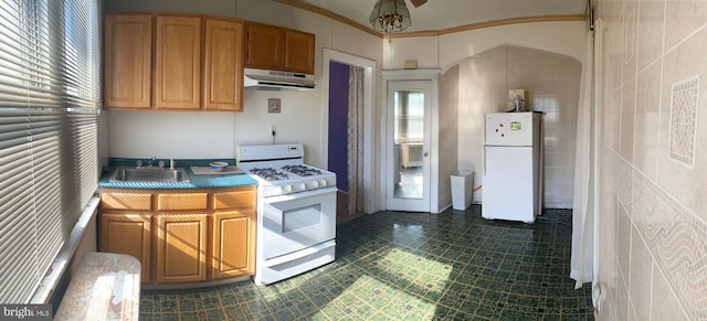 kitchen featuring white appliances, sink, dark tile patterned floors, tile walls, and crown molding