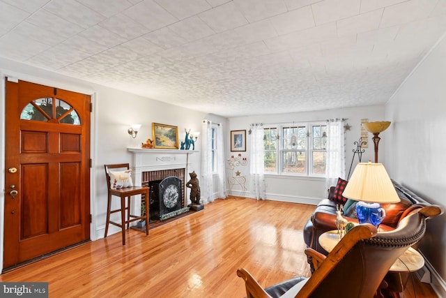 living room with a brick fireplace and light wood-type flooring