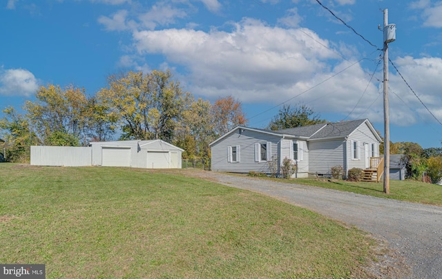 view of side of property with a garage, dirt driveway, an outbuilding, and a lawn