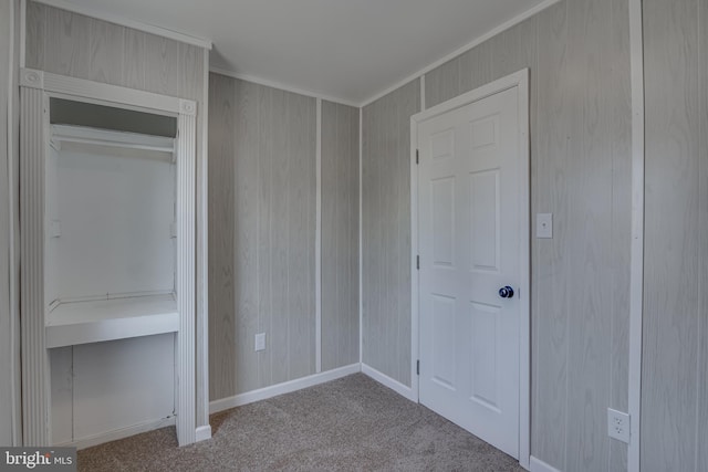 unfurnished bedroom with baseboards, wooden walls, crown molding, and carpet flooring