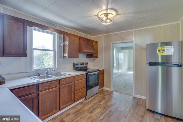 kitchen with custom exhaust hood, appliances with stainless steel finishes, light hardwood / wood-style floors, crown molding, and sink