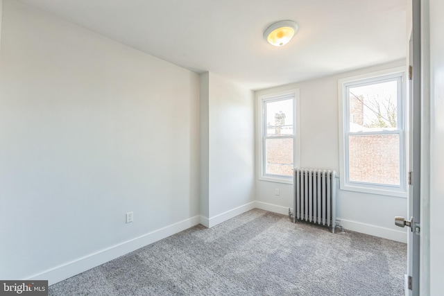 spare room featuring radiator heating unit and light colored carpet