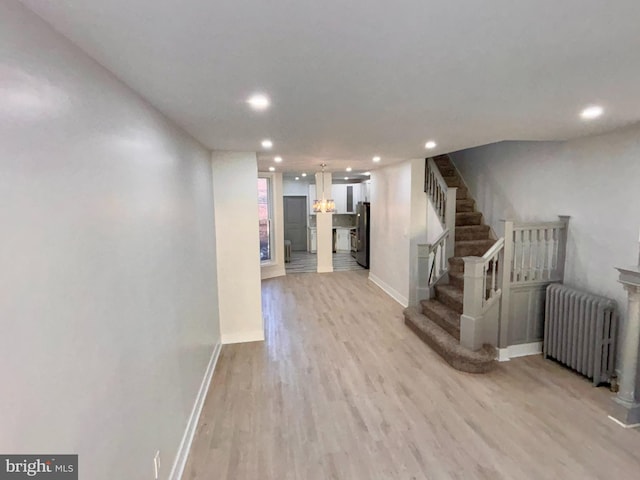 interior space featuring stainless steel fridge, radiator heating unit, and light wood-type flooring