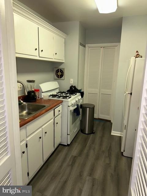 kitchen with sink, white cabinets, white appliances, and dark hardwood / wood-style flooring