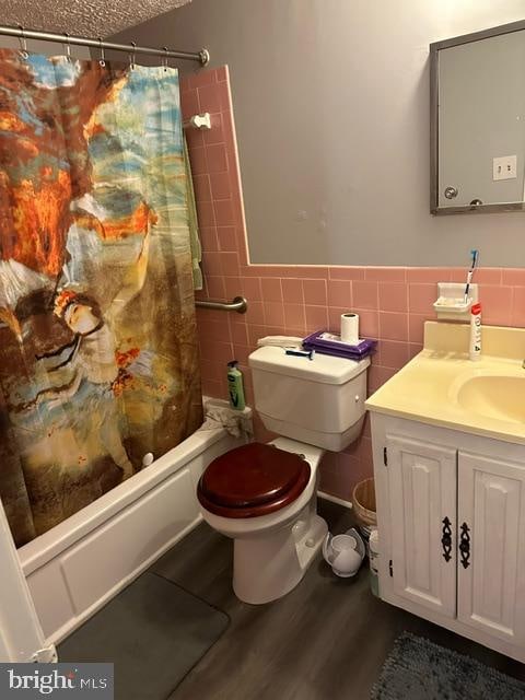 full bathroom with vanity, toilet, tile walls, and shower / tub combo