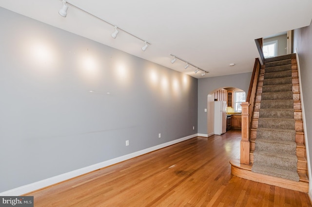 empty room with wood-type flooring and track lighting