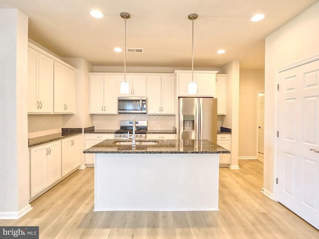 kitchen with stainless steel appliances, light hardwood / wood-style flooring, an island with sink, and hanging light fixtures