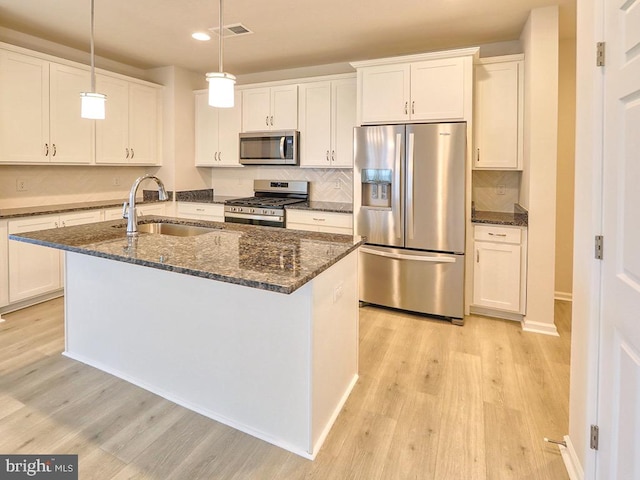 kitchen with sink, appliances with stainless steel finishes, a kitchen island with sink, and white cabinets