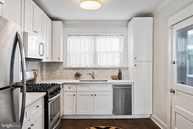 kitchen with decorative backsplash, stainless steel appliances, crown molding, sink, and white cabinets