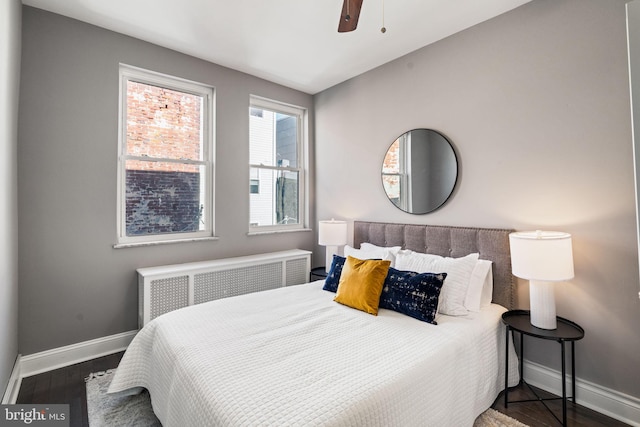 bedroom featuring ceiling fan, radiator heating unit, and dark hardwood / wood-style floors