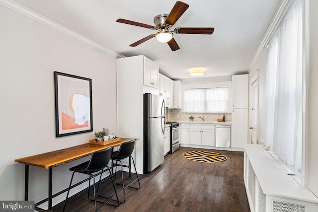 kitchen with appliances with stainless steel finishes, tasteful backsplash, crown molding, white cabinetry, and a breakfast bar area