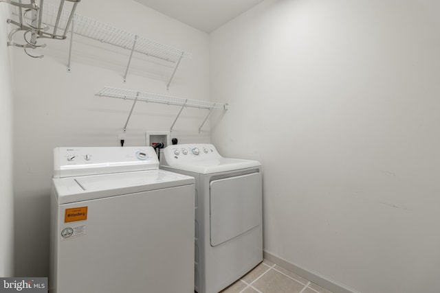 washroom featuring laundry area, baseboards, separate washer and dryer, and light tile patterned flooring