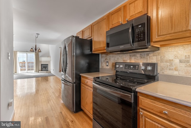 kitchen with light countertops, tasteful backsplash, range with electric stovetop, and light wood-type flooring