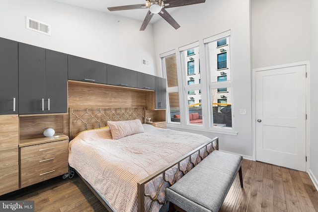 bedroom featuring ceiling fan, a high ceiling, and dark hardwood / wood-style flooring