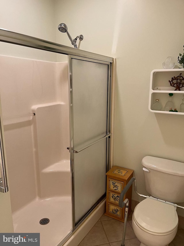 bathroom featuring toilet, tile patterned flooring, and a shower with door