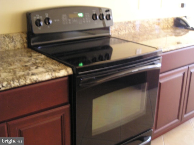 kitchen featuring light stone counters, light tile patterned flooring, and electric range