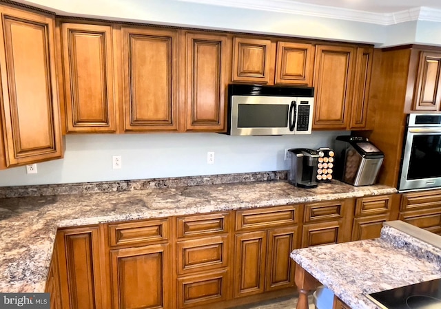 kitchen featuring light stone counters, appliances with stainless steel finishes, and ornamental molding