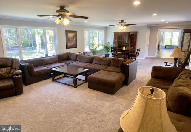 carpeted living room featuring ornamental molding, ceiling fan, and plenty of natural light