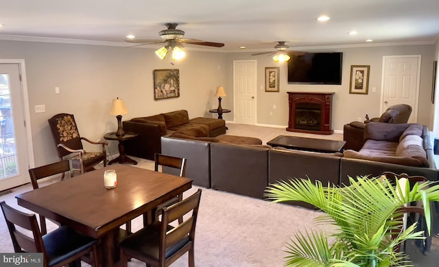 carpeted dining area with crown molding and ceiling fan