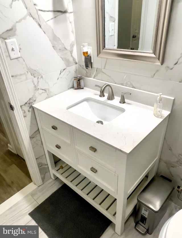 bathroom with vanity, toilet, tile walls, and wood-type flooring