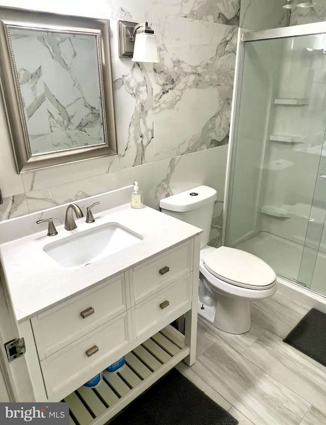 bathroom with vanity, an enclosed shower, toilet, and tile walls