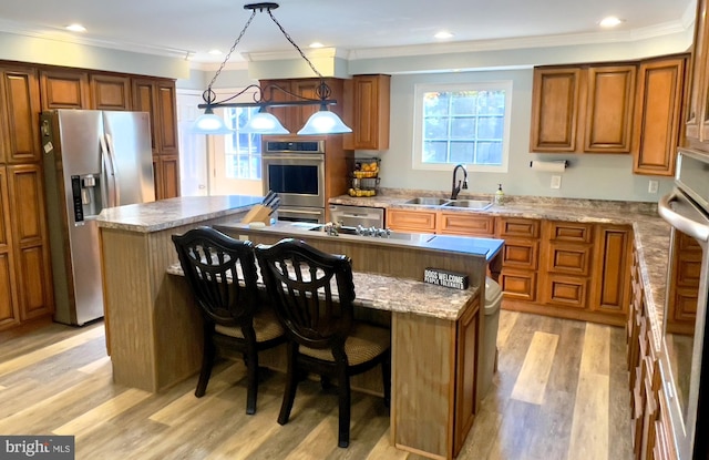 kitchen featuring appliances with stainless steel finishes, sink, a center island, and pendant lighting