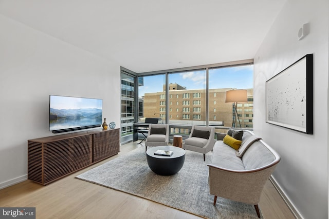 living room featuring hardwood / wood-style flooring, a healthy amount of sunlight, and a wall of windows