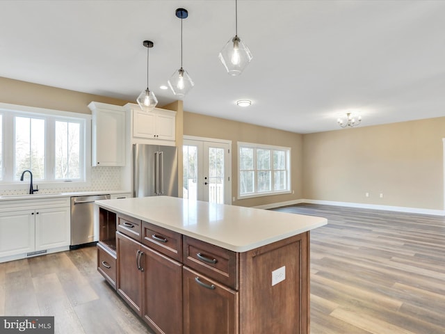 kitchen featuring a wealth of natural light, white cabinetry, sink, and appliances with stainless steel finishes