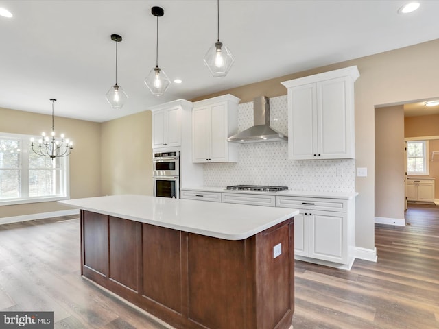 kitchen with white cabinets, appliances with stainless steel finishes, and wall chimney range hood