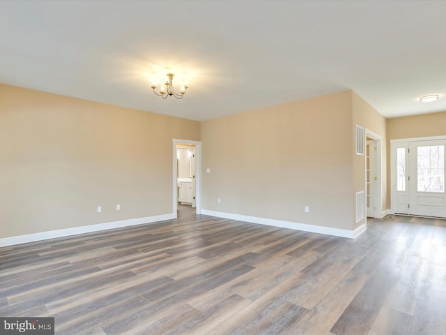 unfurnished room featuring wood-type flooring and an inviting chandelier