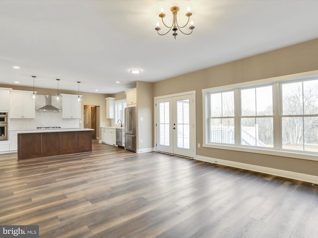 unfurnished living room featuring french doors, dark hardwood / wood-style flooring, an inviting chandelier, and sink