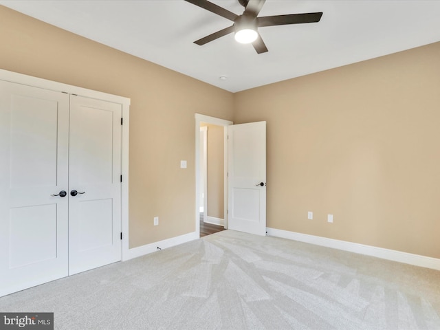 unfurnished bedroom with ceiling fan, a closet, and light carpet