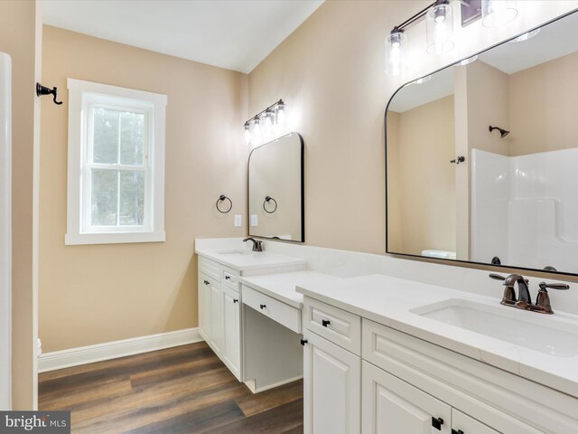 bathroom featuring hardwood / wood-style floors, vanity, toilet, and a shower