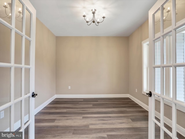 empty room featuring dark hardwood / wood-style flooring and an inviting chandelier