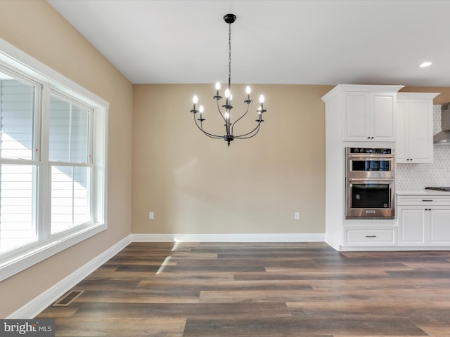 unfurnished dining area featuring dark hardwood / wood-style floors and an inviting chandelier