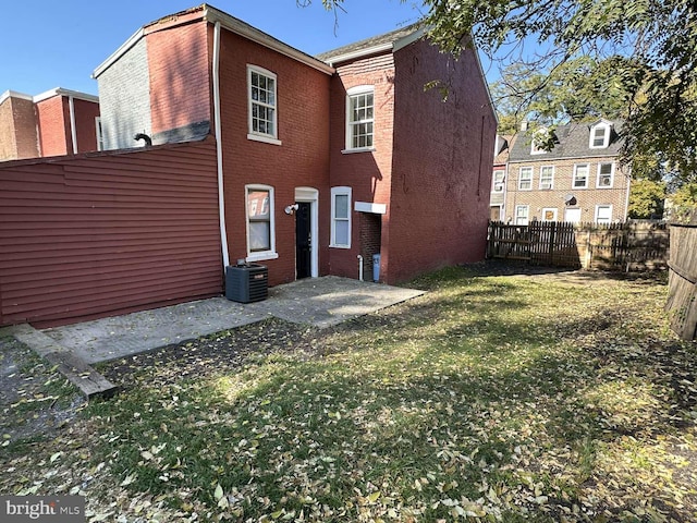 rear view of property featuring central air condition unit and a lawn