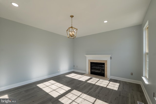 unfurnished living room with a notable chandelier and dark hardwood / wood-style flooring