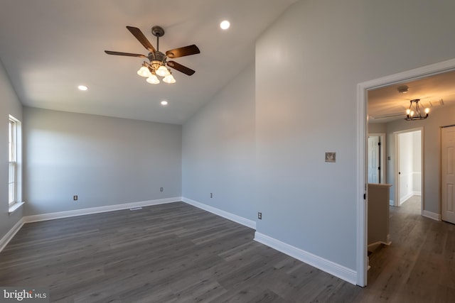 empty room featuring vaulted ceiling, dark hardwood / wood-style floors, and ceiling fan with notable chandelier