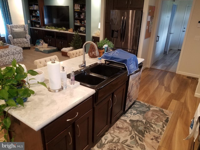 kitchen with stainless steel fridge, sink, light hardwood / wood-style floors, and dark brown cabinets