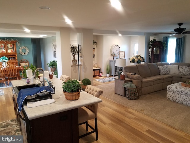 living room featuring ceiling fan, light wood-type flooring, and sink