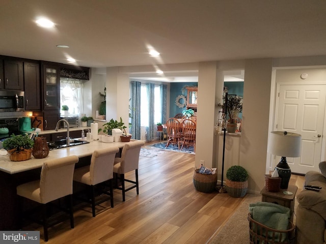 kitchen featuring a kitchen bar, kitchen peninsula, sink, electric range, and light hardwood / wood-style flooring