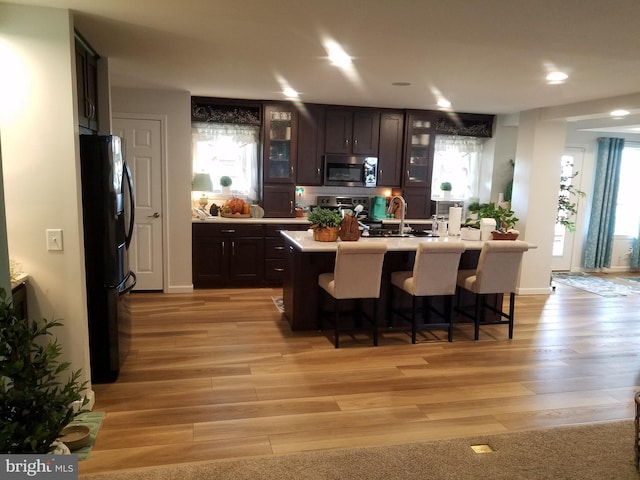 kitchen with appliances with stainless steel finishes, a center island with sink, plenty of natural light, and light hardwood / wood-style floors