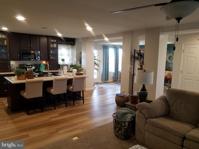 kitchen with dark brown cabinetry, a center island with sink, black / electric stove, and light wood-type flooring