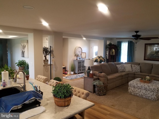 living room featuring ceiling fan, light hardwood / wood-style flooring, and sink