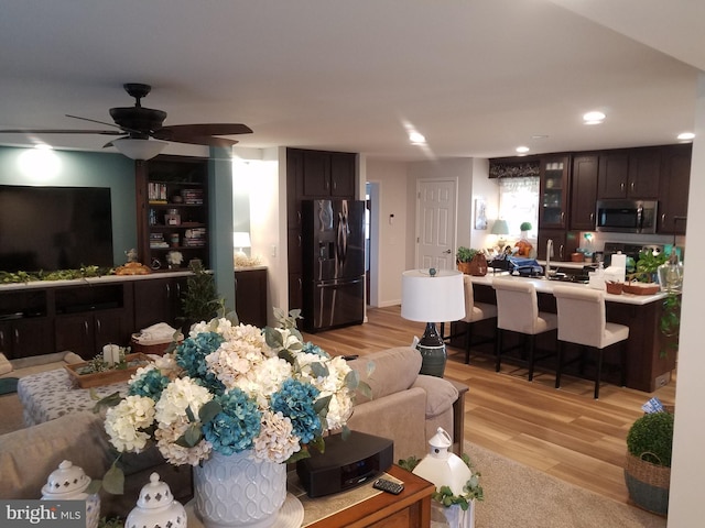 living room featuring ceiling fan, light hardwood / wood-style flooring, and sink