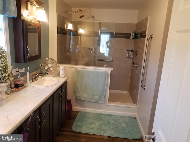 bathroom featuring a tile shower, vanity, and wood-type flooring