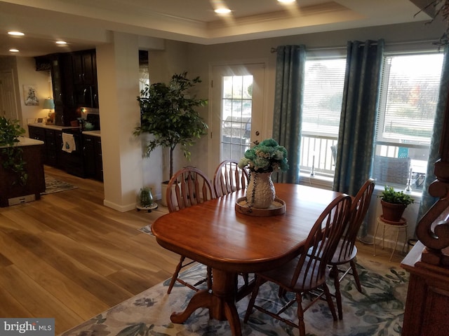 dining room featuring light hardwood / wood-style floors, ornamental molding, and a tray ceiling